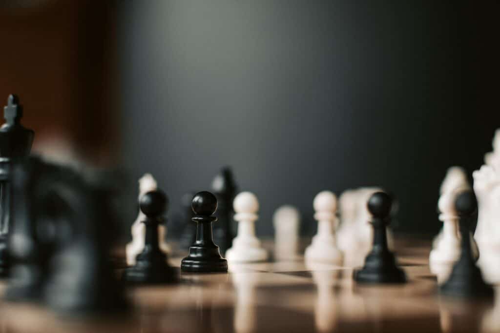 Close-up of black and white chess pieces on a chessboard, highlighting strategic gameplay.