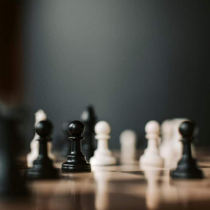 Close-up of black and white chess pieces on a chessboard, highlighting strategic gameplay.